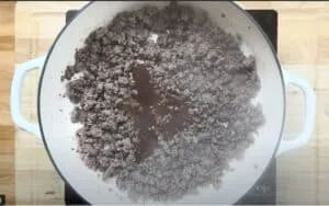 Cooking ground beef in a pan on a stovetop for a savory dish.